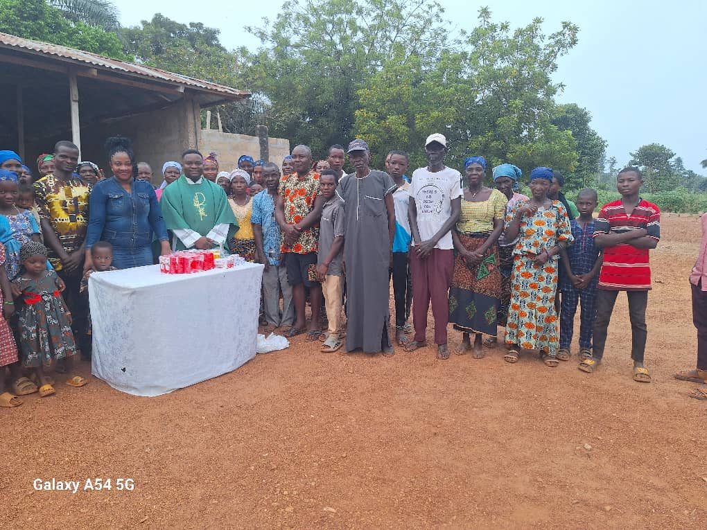 Nurse Vivian Okafor with a parish priest and an entire rural community gathered around a table of donated supplies