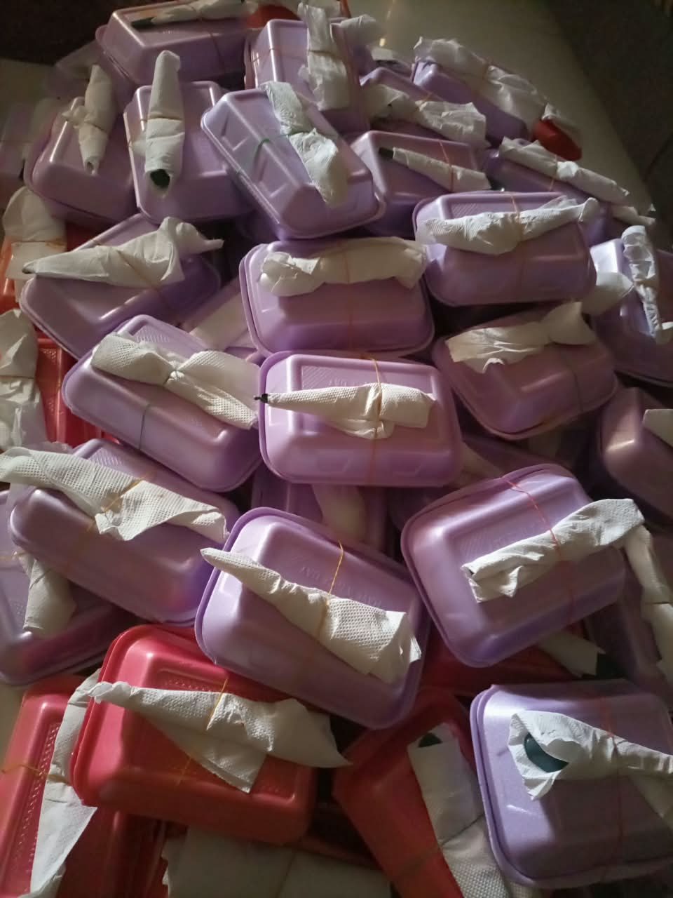 Dozens of packed hot meals, each tied with cutlery wrapped in a napkin